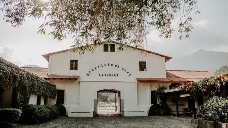 Charming historic building of Beneficio de Cafe La Azotea surrounded by lush greenery and cobblestones.